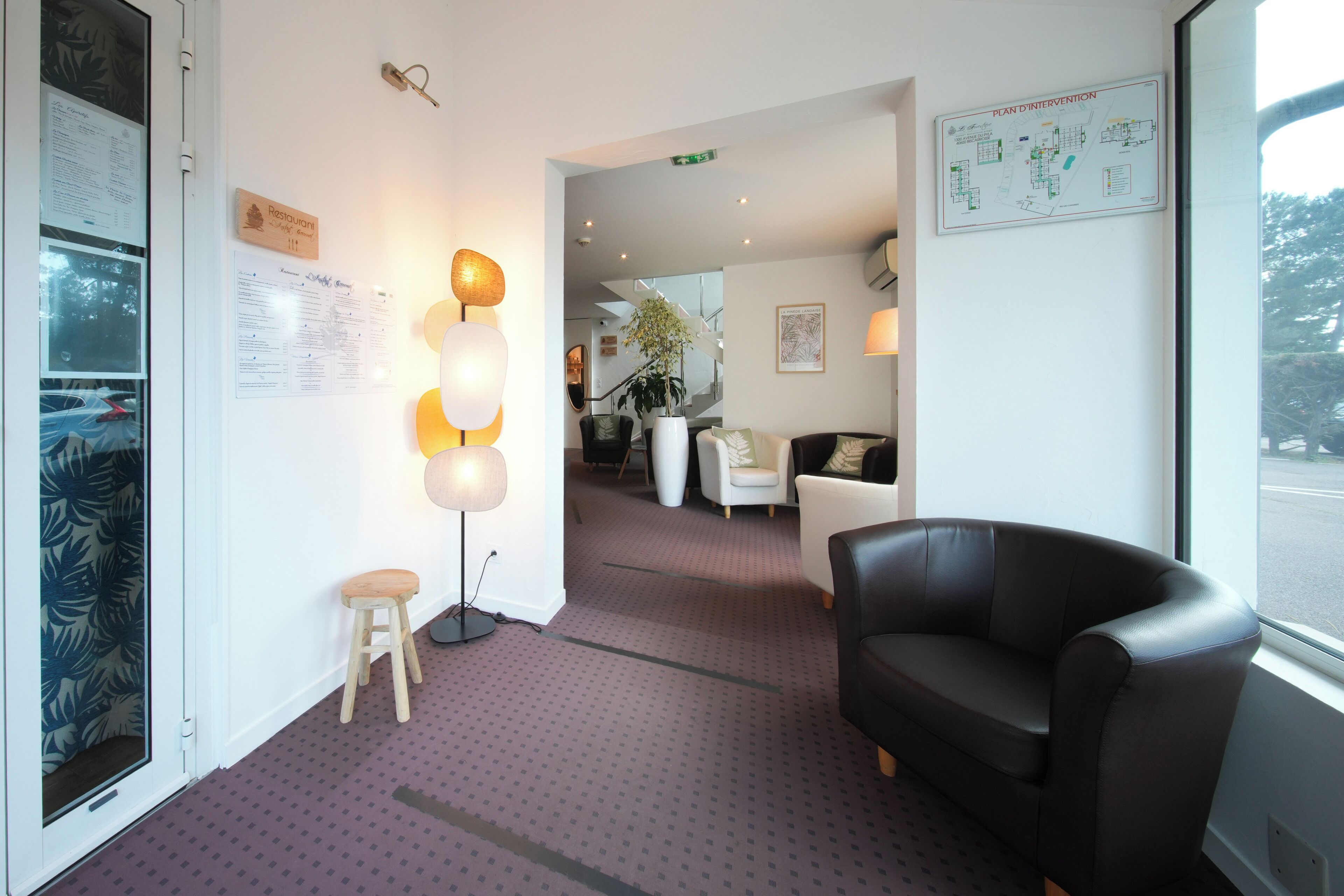 Un hall d’hôtel comprenant un comptoir d’accueil, un espace salon et une grande fenêtre.