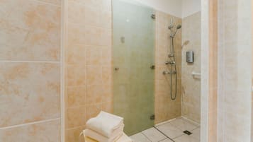 A bathroom with a glass shower door, a towel stack, and a handheld showerhead.