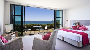 A modern hotel room with a large balcony, a bed, a TV, and a view of the sea. - Doubtless Bay Villas (Cable Bay)