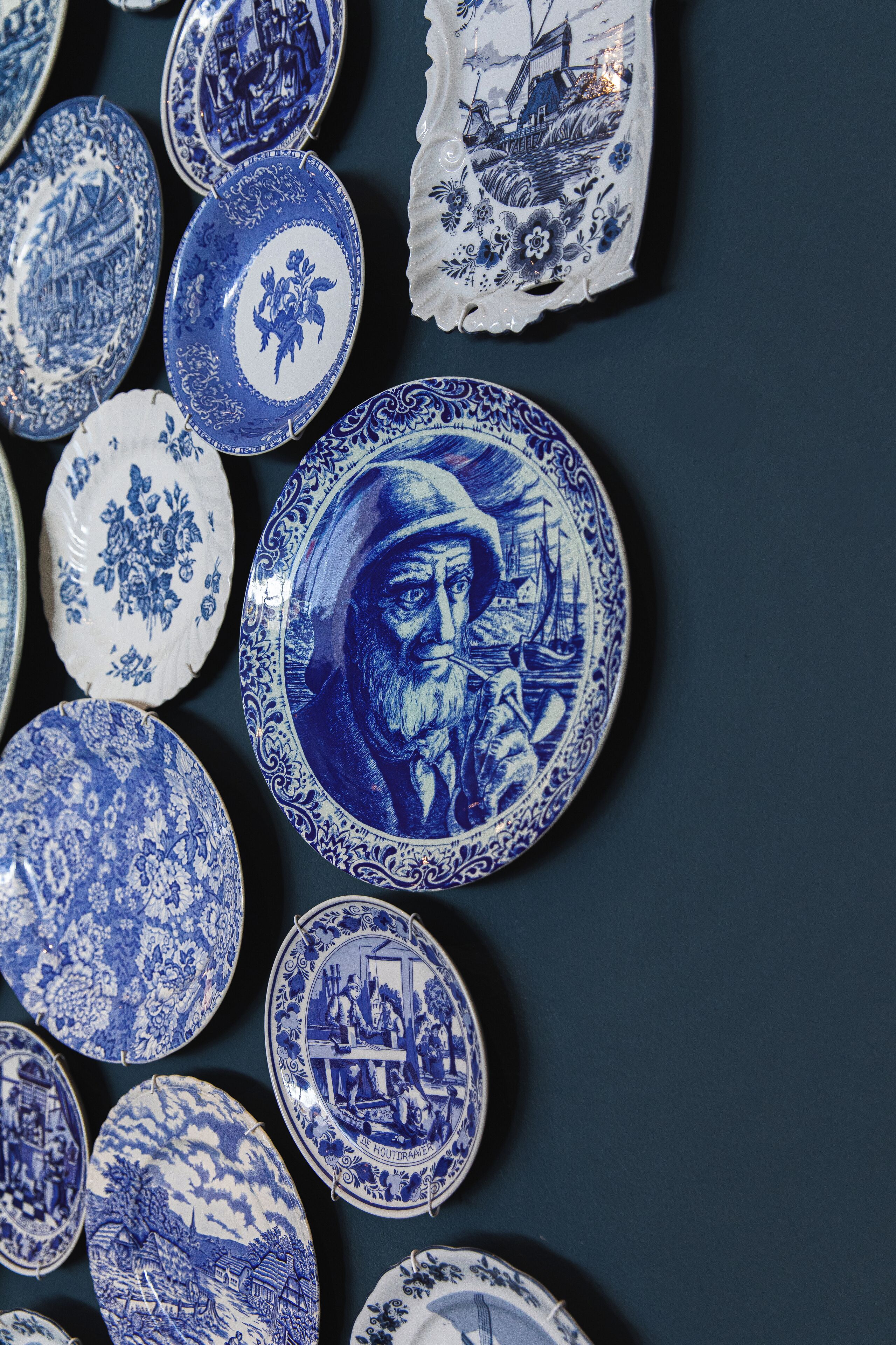 Una colección de platos de cerámica azul y blanco con diversos diseños, entre ellos motivos florales y escenas marinas.