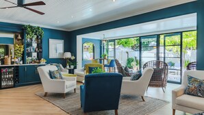Una sala de estar moderna con una pared azul destacada, una zona de bar con enfriador de vino y ventanas amplias que ofrecen vistas al exterior.
