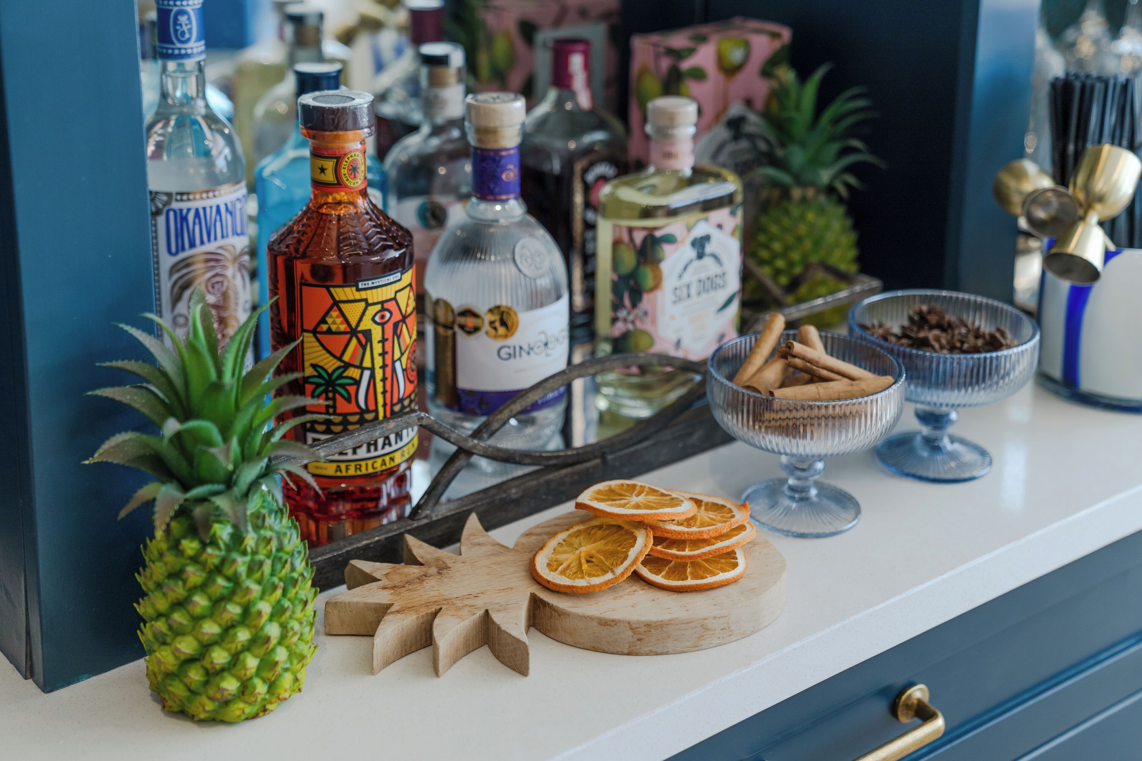 A bar area with various bottles, a pineapple, dried orange slices, and a star-shaped cutting board.