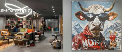 Een modern interieur met een gezellige zithoek, een zichtbare trap en een groot kunstwerk van een koe met zonnebril.
