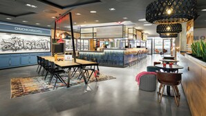 A modern interior with a bar area, seating arrangements, and a mural on the wall. - Moxy Zurich (Zürich)