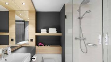 Un baño moderno con un espejo grande, dos lavamanos, una ducha y un inodoro.