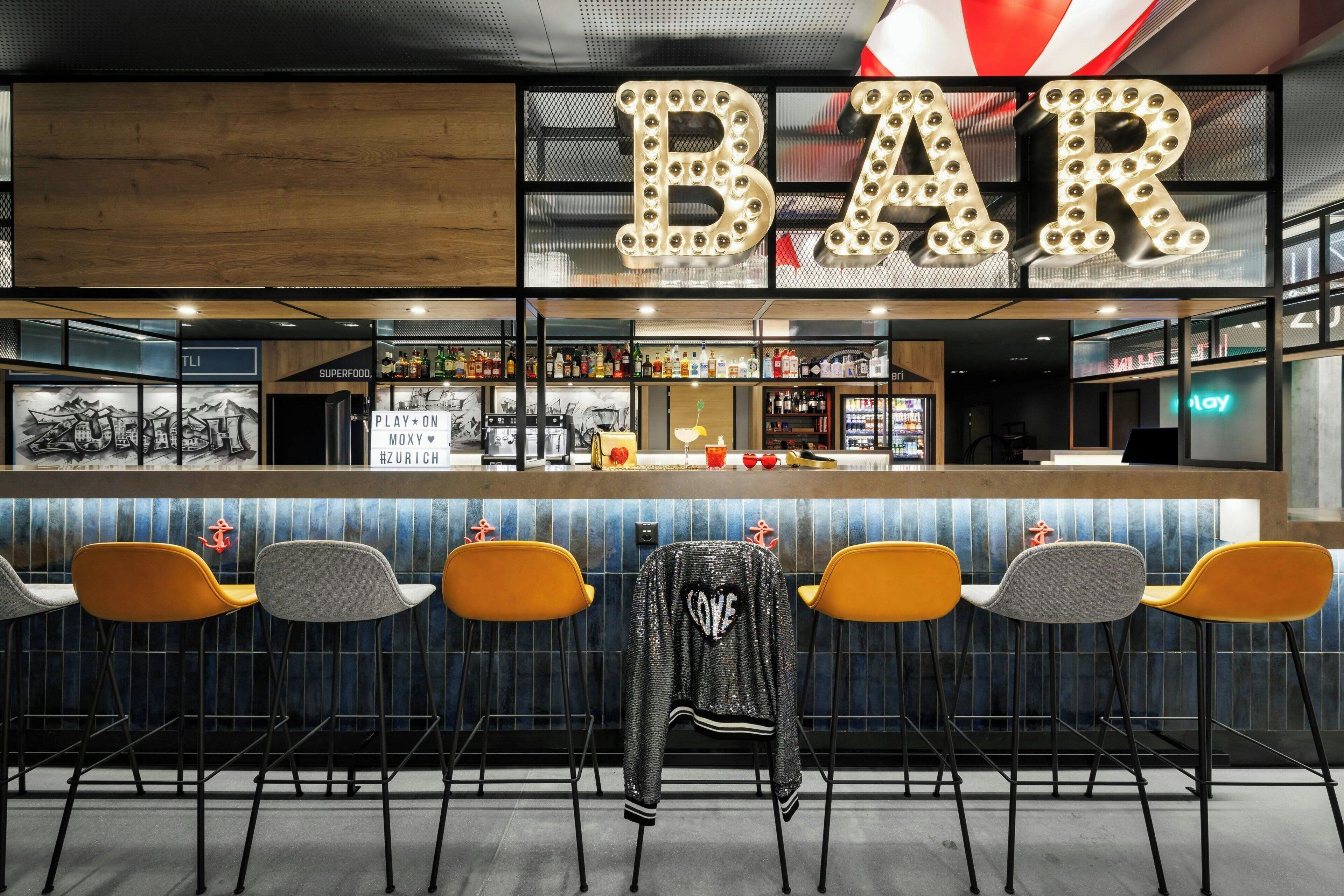 A bar area with a counter, bar stools, and a jacket hanging on the wall.