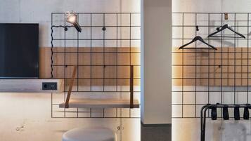 A modern bathroom with a wooden shelf, a hanging light fixture, and a towel rack.