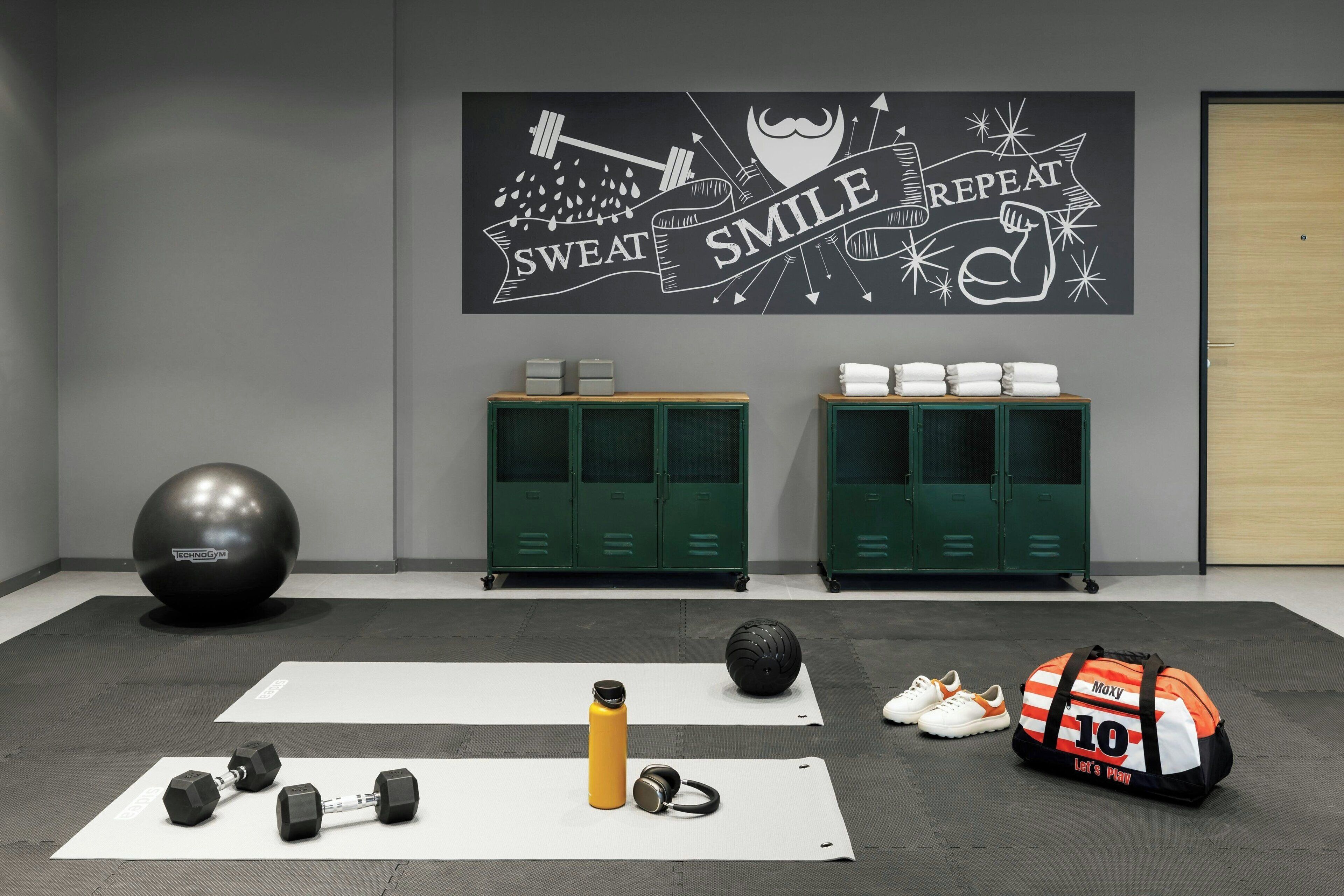 Une salle de sport équipée de matériel d’exercice, de tapis et de casiers.