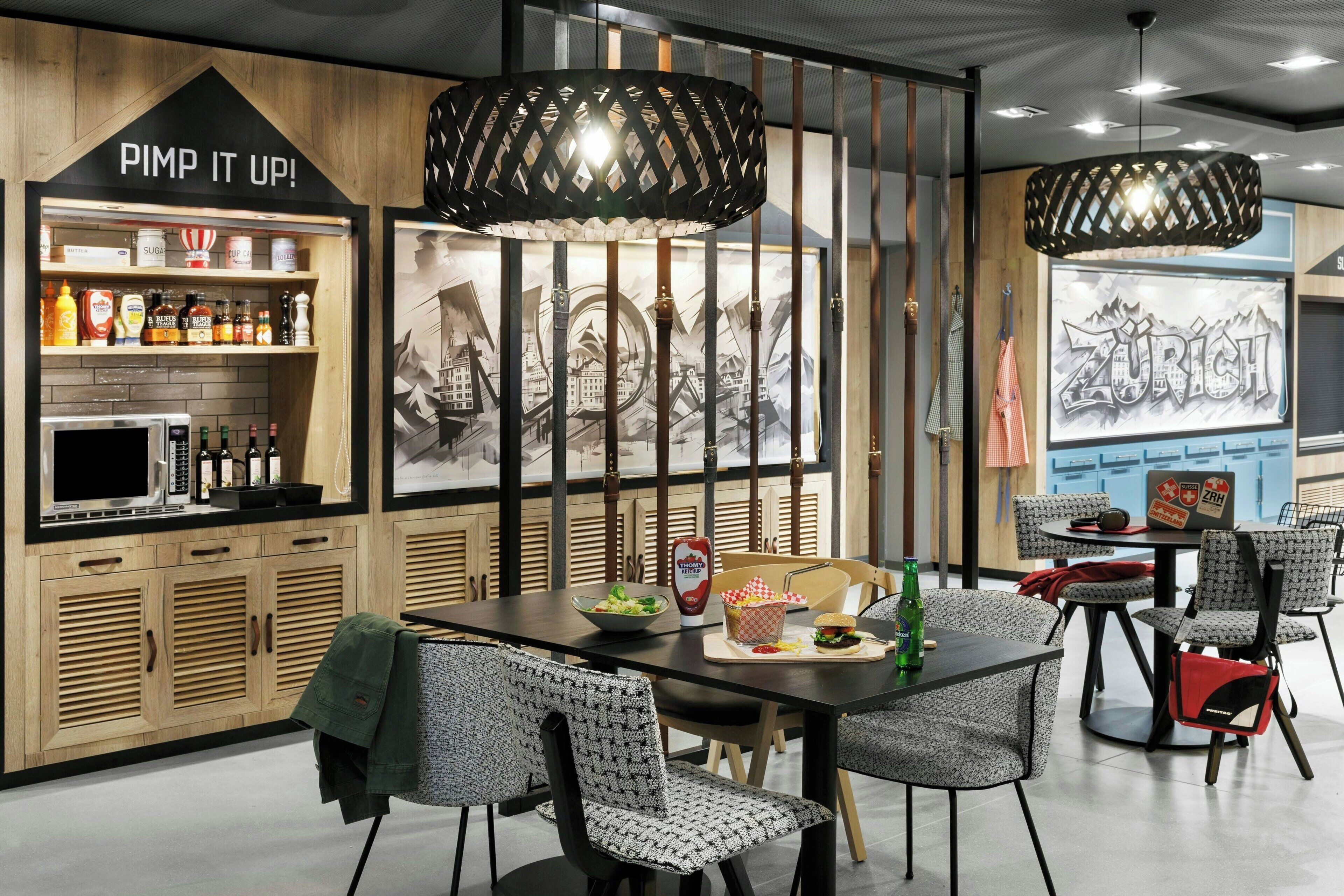 A modern restaurant with wooden cabinetry, a black countertop, and a seating area with patterned chairs.