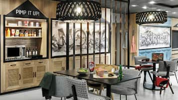 A modern restaurant with wooden cabinetry, a black countertop, and a seating area with patterned chairs.