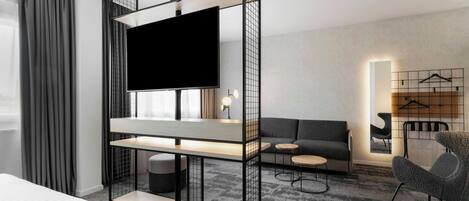 Una habitación de hotel moderna con una cama, un televisor en un mueble bajo, un sofá, una mesita y una silla.