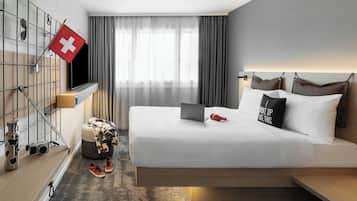 A modern hotel room with a bed, a laptop, a Swiss flag, a TV, and a window with curtains.