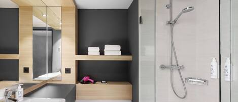 A modern bathroom with a glass-enclosed shower, a sink, a toilet, and a mirror.