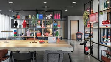 A modern interior with a wooden table, chairs, and shelves with various items including a laptop, books, and decorative objects.