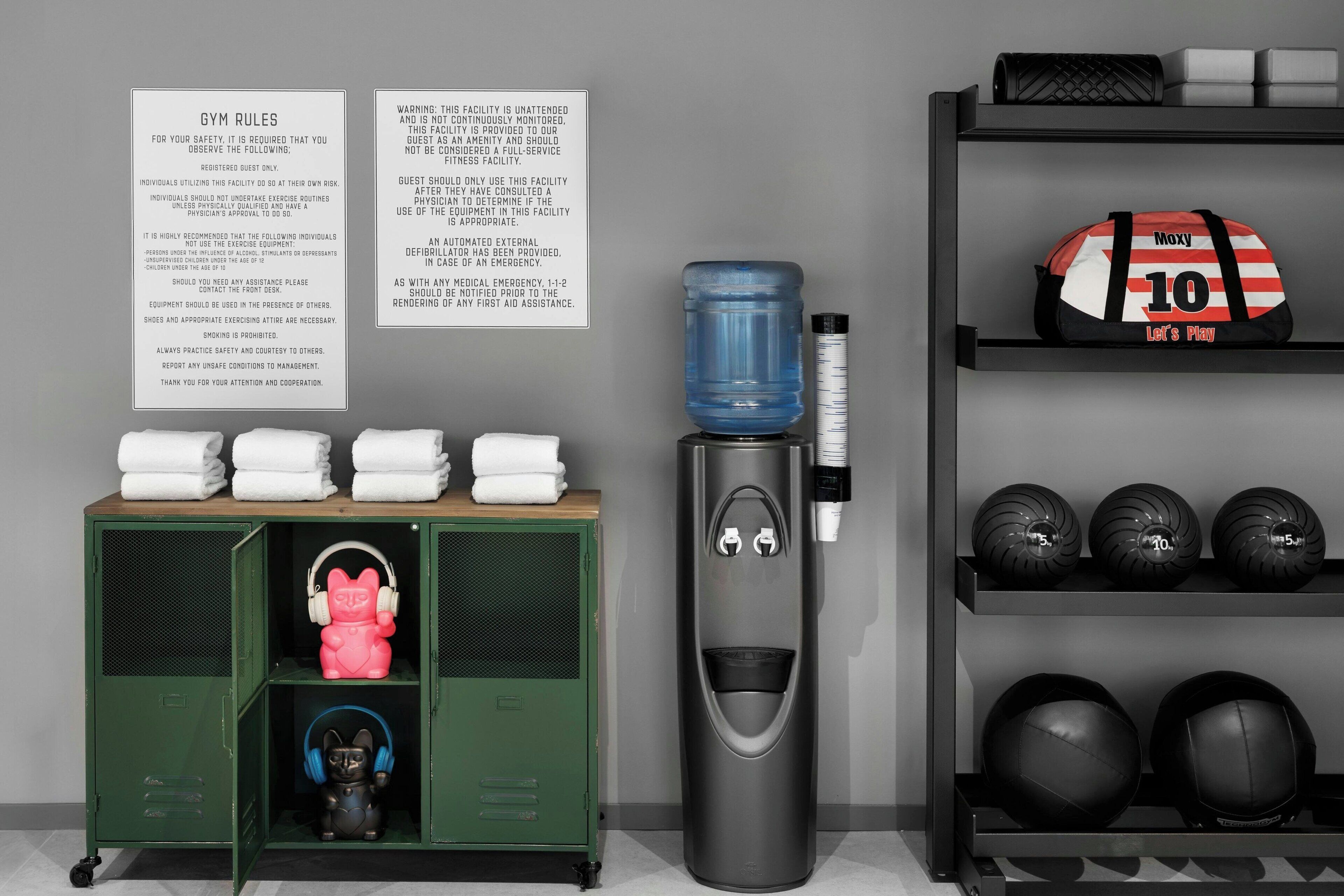 Une salle de sport équipée d’un distributeur d’eau, d’appareils d’exercice et d’un porte-serviettes.