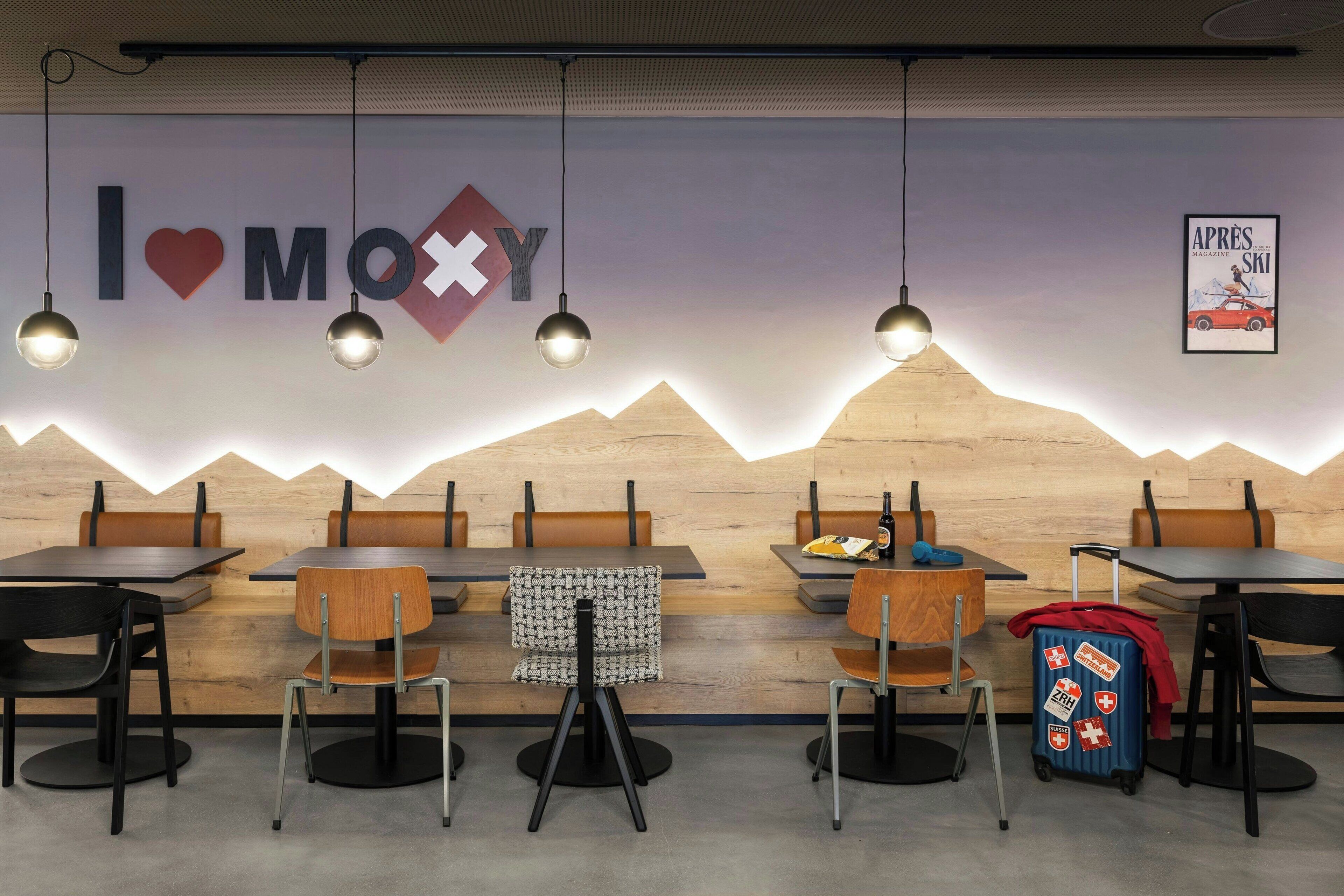 Un restaurante con un diseño de pared al estilo de montaña, mesas y sillas de madera, y un tablero de menú a la vista.