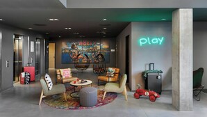 A modern lobby with seating, a neon sign, and a mural. - Moxy Zurich (Zürich)