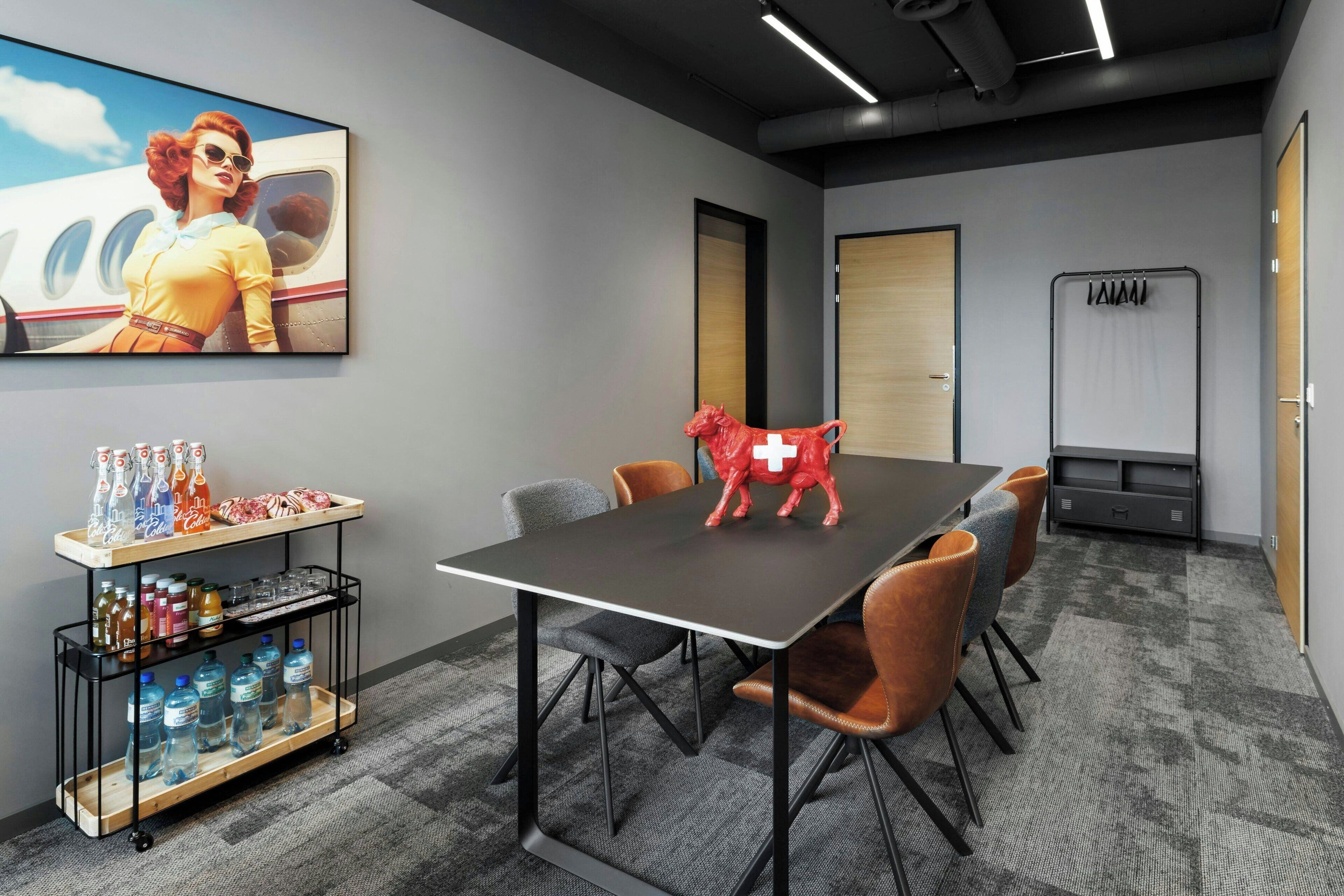A conference room with a table, chairs, a water dispenser, and a red horse sculpture.