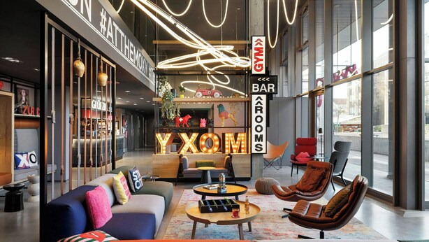 A modern interior with a bar area, seating, and a large illuminated sign. - Moxy Zurich (Zürich)