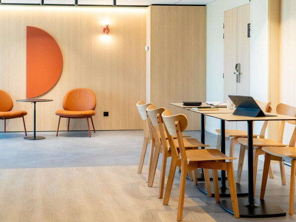 Una sala de conferencias moderna con una larga mesa, sillas de madera y un ordenador portátil sobre la mesa.