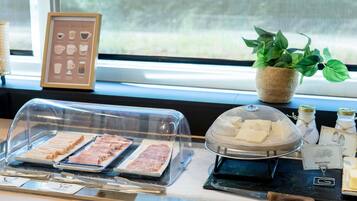 Un comptoir où l’on sert le petit-déjeuner, avec un assortiment de viandes, une plante et un panneau indiquant « Beurre doux ».