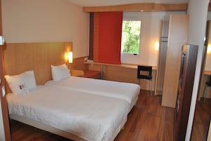 Habitación de hotel con una cama grande, un escritorio, una silla y un refrigerador.