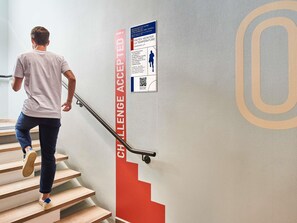 Una persona bajando una escalera con un cartel rojo que dice 'CHALLENGE ACCEPTED!' en la pared.