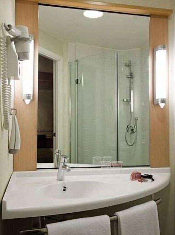 A modern bathroom with a large mirror, a sink, and a shower. - ibis Loriol Le Pouzin (Le Pouzin)