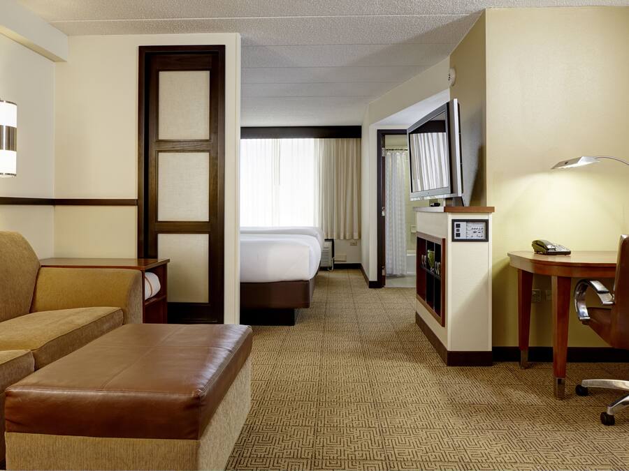Habitación de hotel con sofá, una mesita, escritorio, silla, cama, televisor y lámpara.