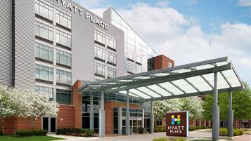 A modern hotel with a glass entrance, a covered walkway, and a sign indicating it's a Hyatt Place.