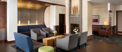 A lobby with seating, a fireplace, and a modern design.