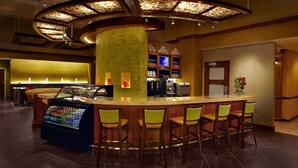 A bar area with a counter, stools, a beverage dispenser, and a television. - Hyatt Place Columbus/OSU (Columbus)
