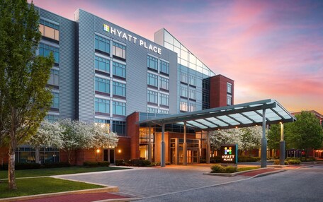 A modern hotel building with a glass facade, a covered entrance, and a sign indicating it's a Hyatt Place.