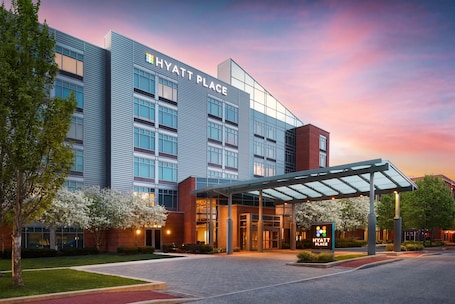 A modern hotel building with a glass facade, a covered entrance, and a sign indicating it's a Hyatt Place.