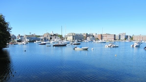 A marina with various boats docked, surrounded by buildings and a clear sky.