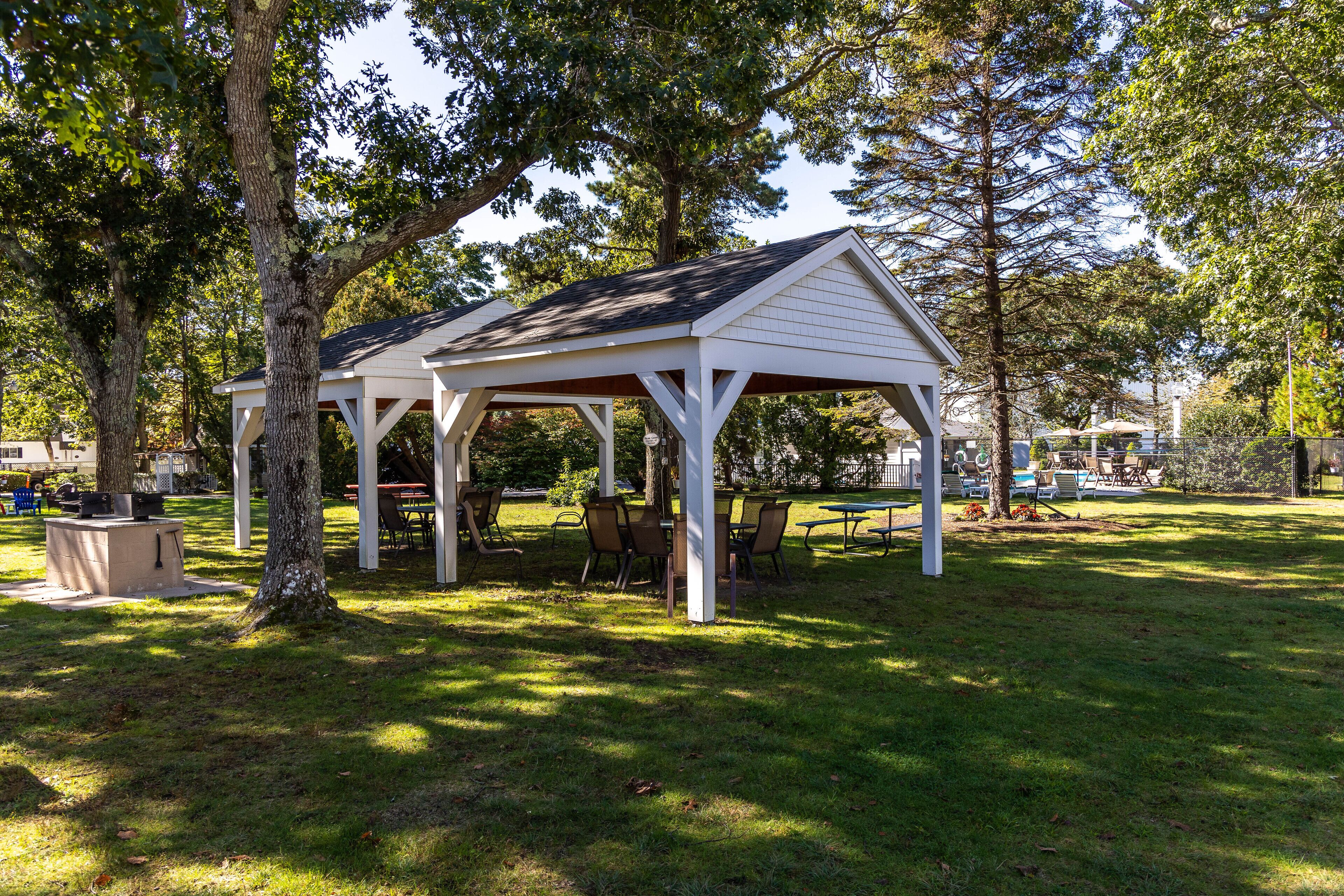 Ein überdachter Pavillon mit Dach, umgeben von Bäumen und Gras.