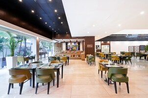 Un restaurante moderno con una barra central, varias mesas y sillas para comer.