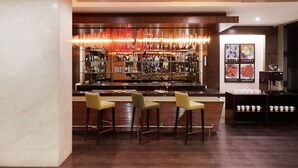Zona de bar con diseño moderno, que incluye una barra larga, diversas opciones de asientos y una variedad de bebidas.