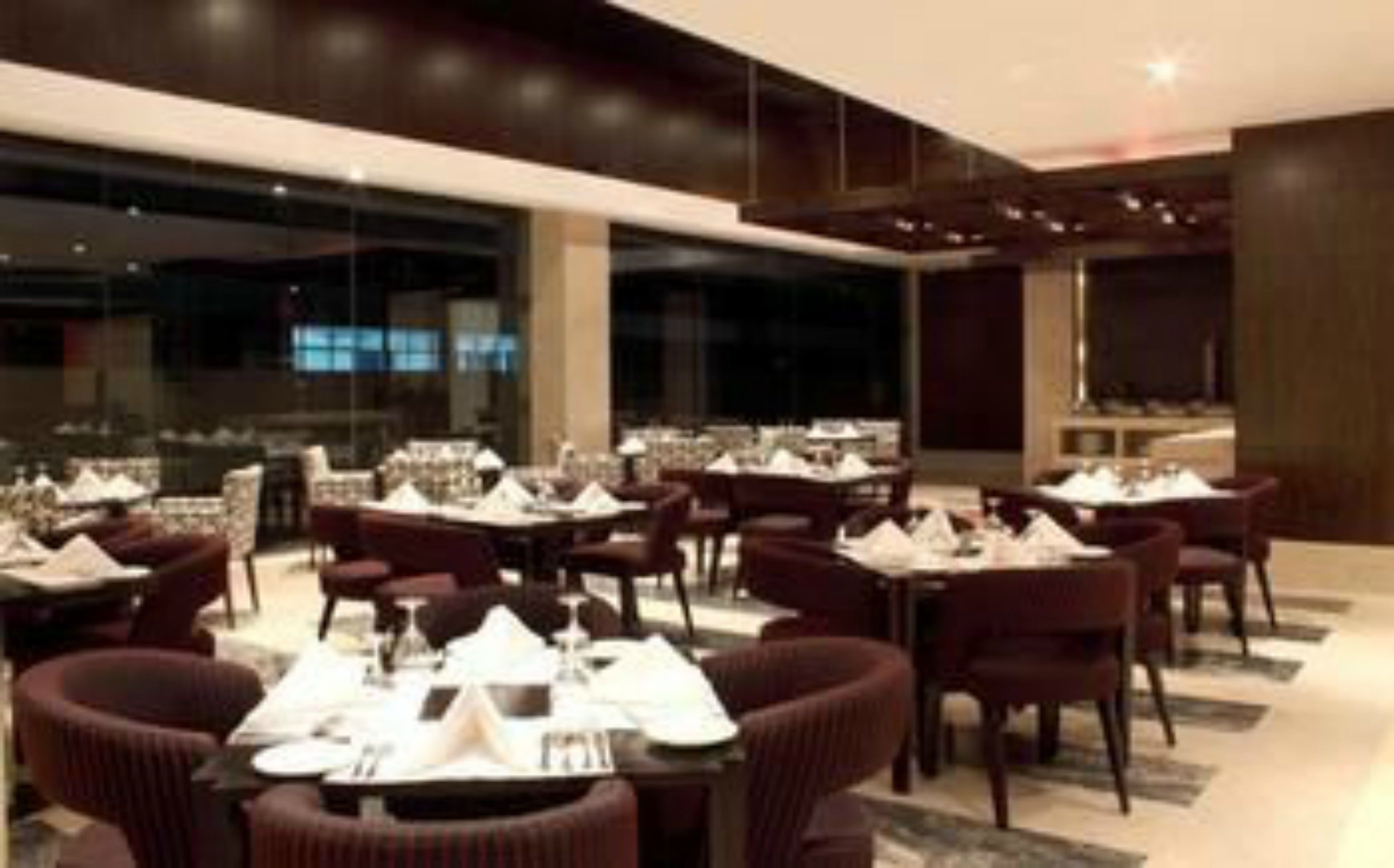 A modern restaurant with multiple tables and chairs, large windows, and a clean, contemporary design.