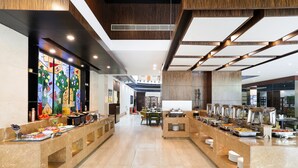 Un moderno vestíbulo de hotel con zona de bufé, suelo de mármol y decoración contemporánea.