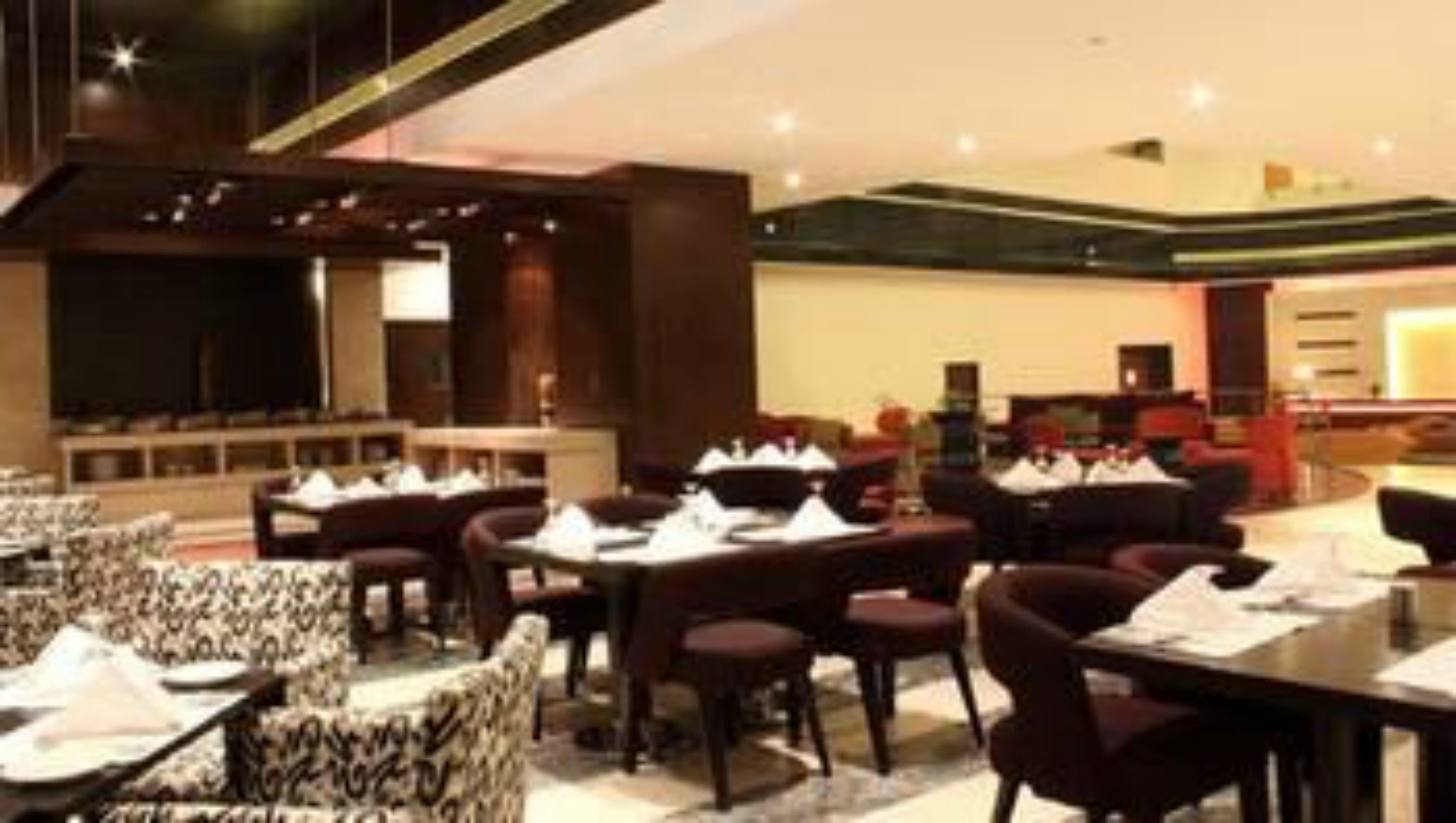 A modern dining area with round tables and chairs, a bar area, and a reception desk.