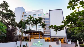Un hotel moderno con un letrero que dice "lemon tree hotel", rodeado de follaje y palmeras.