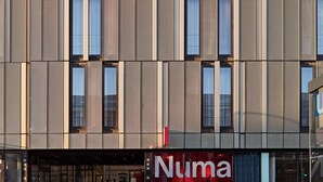 Une façade de bâtiment moderne, caractérisée par un motif en briques et de grandes fenêtres.