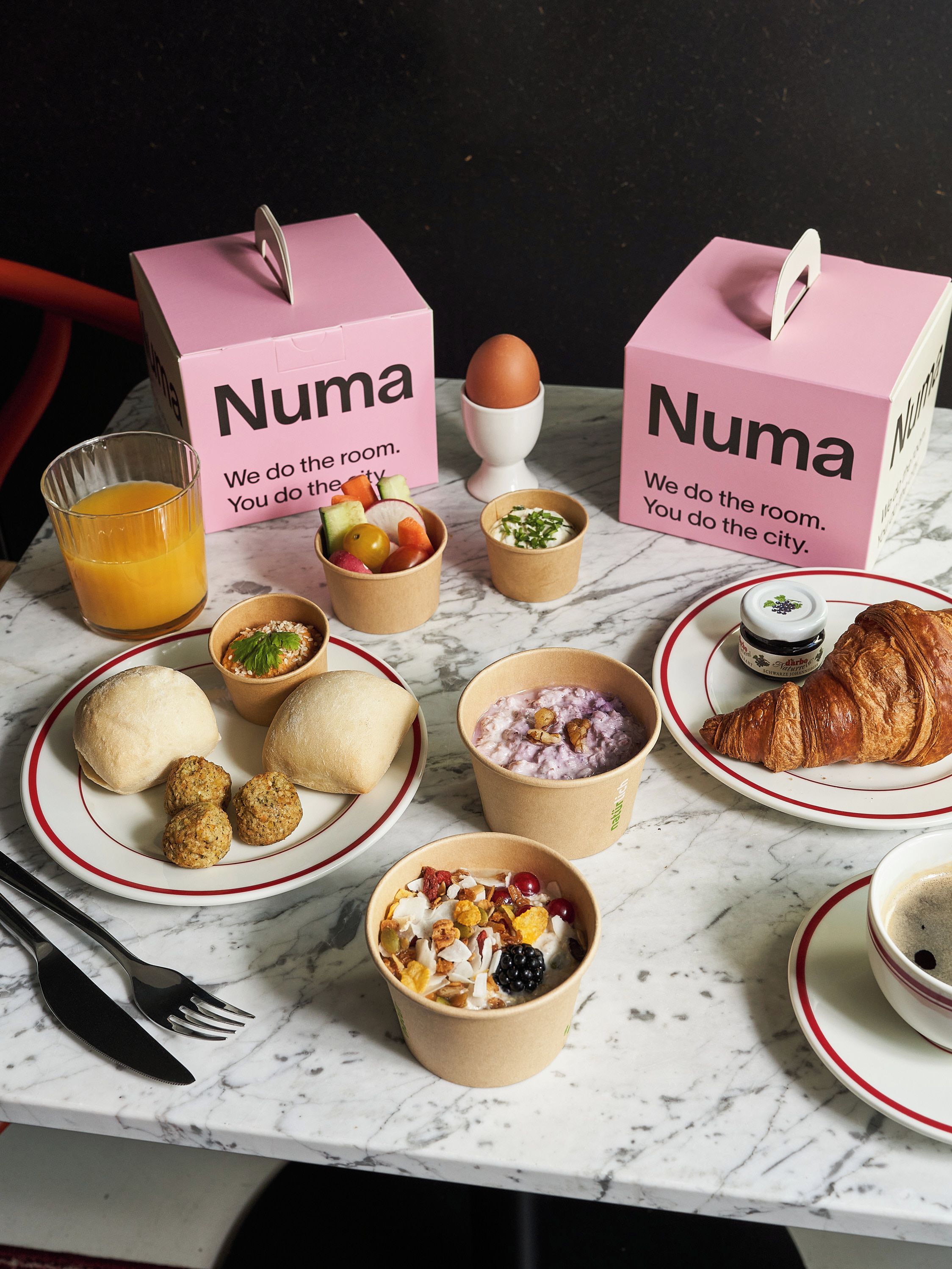 Une table en marbre dressée pour le petit-déjeuner, avec divers aliments et un verre de jus d’orange.