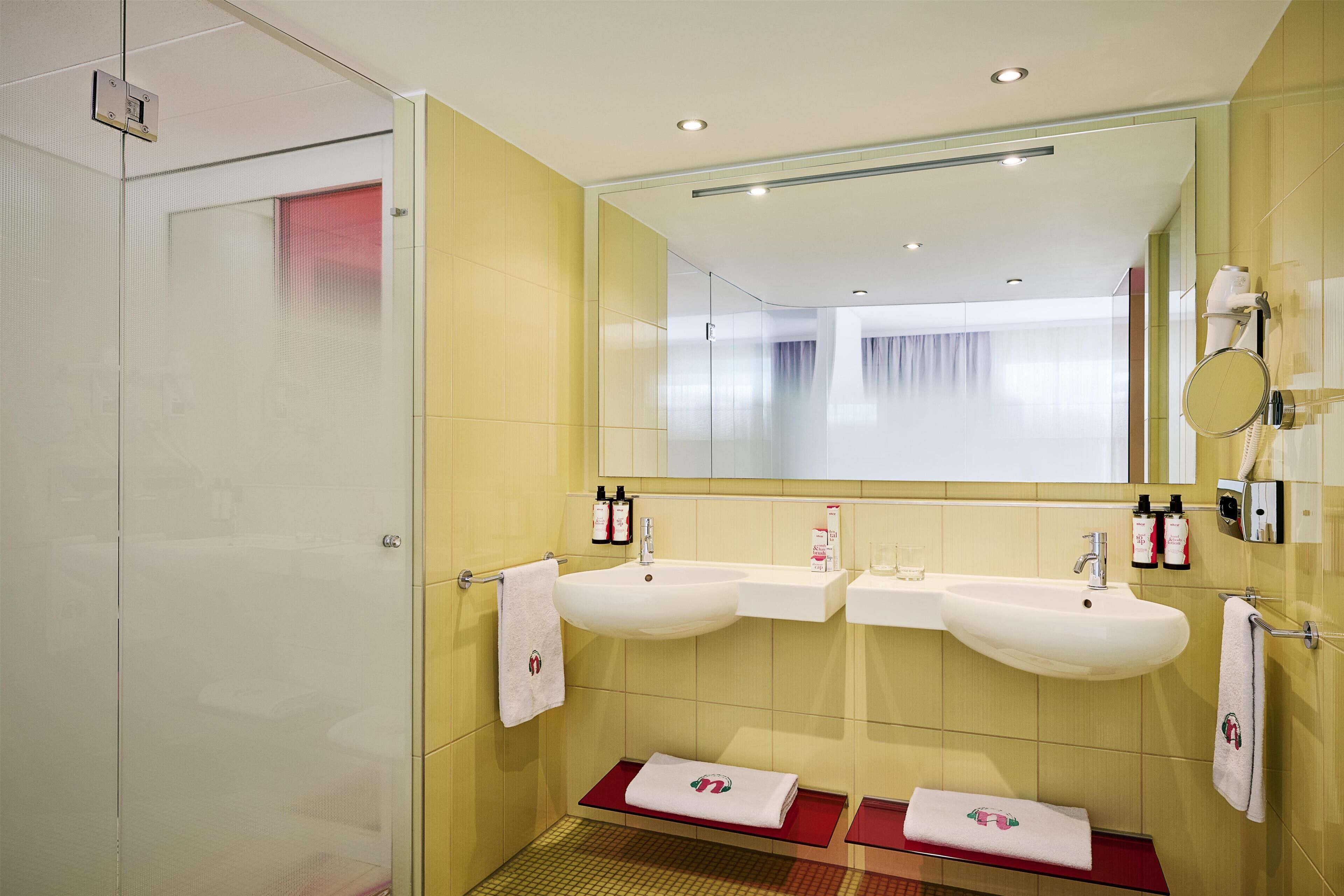 Un baño moderno con dos lavamanos, un espejo grande y una zona de ducha.