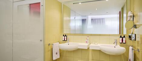 Un baño moderno con dos lavamanos, un espejo grande y una zona de ducha.