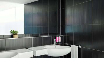 Un baño moderno con paredes de azulejos oscuros, un lavabo blanco y un espejo encima.