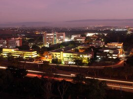 Un paisaje urbano al anochecer con edificios iluminados y una autopista.