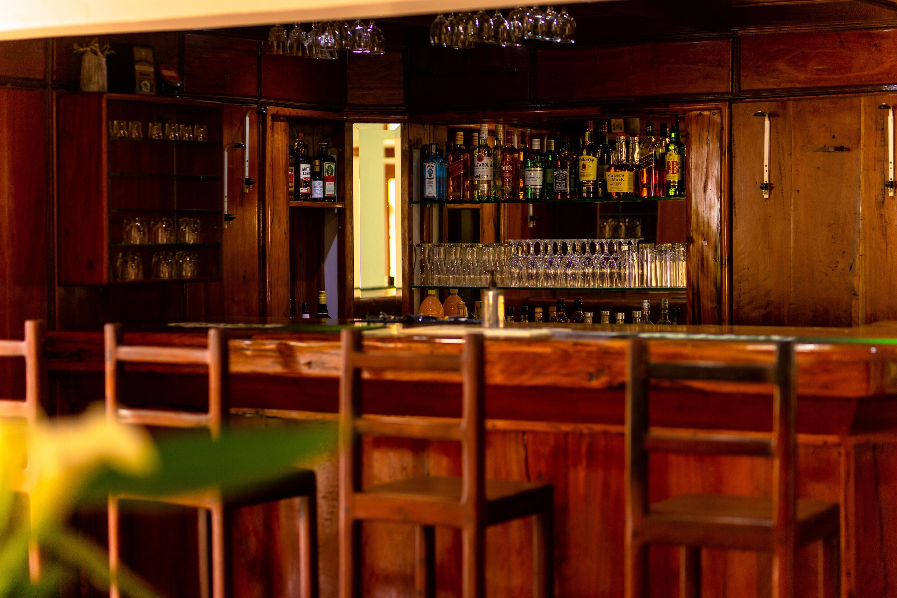 A bar with wooden furniture, shelves with bottles, and glasses.