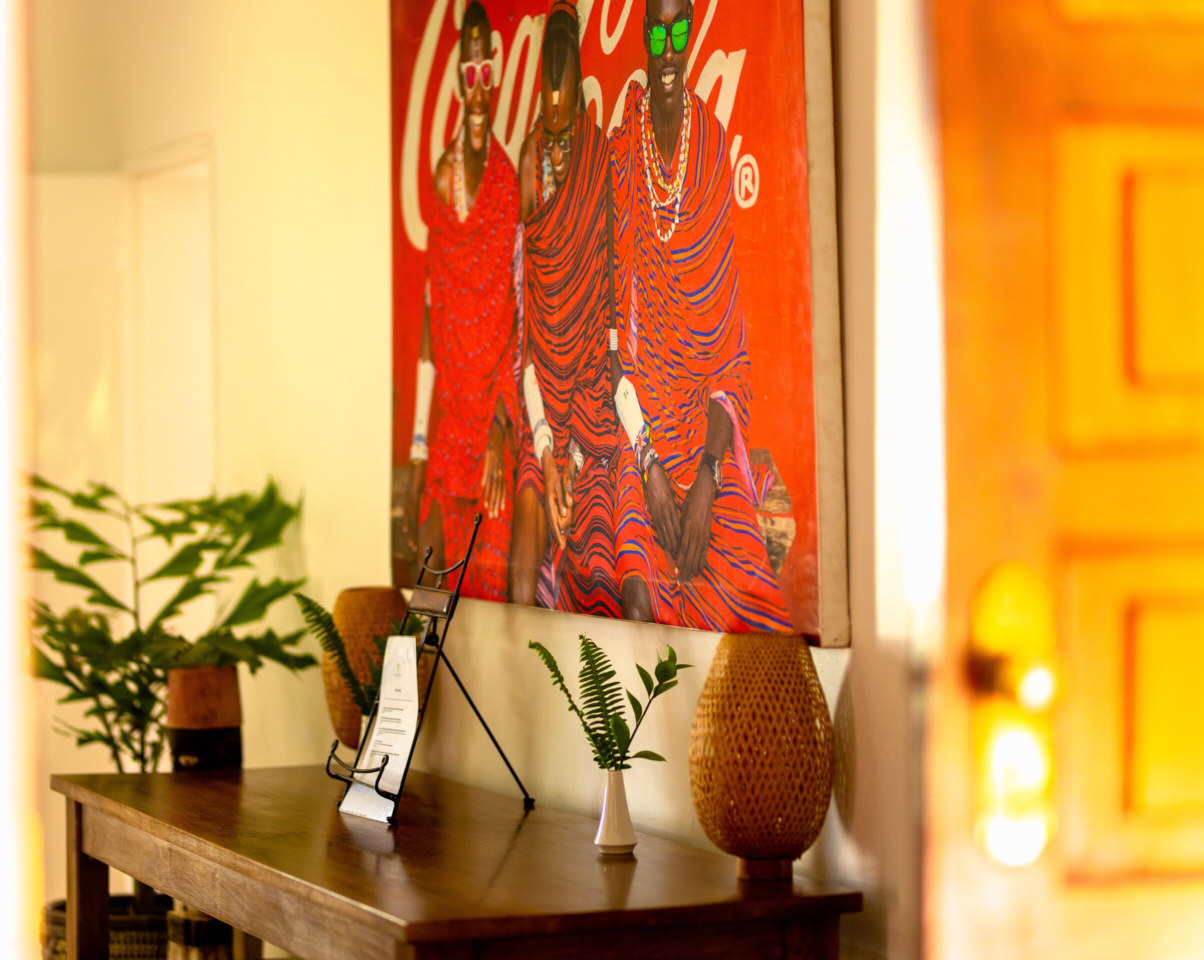 A wooden reception desk with a framed poster, a potted plant, and a small vase.